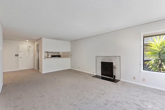 unfurnished living room featuring a fireplace with flush hearth, carpet floors, and a textured ceiling