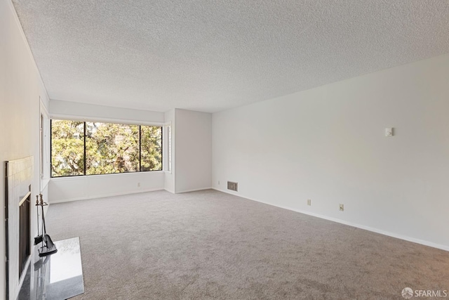 empty room with carpet, baseboards, visible vents, and a tiled fireplace