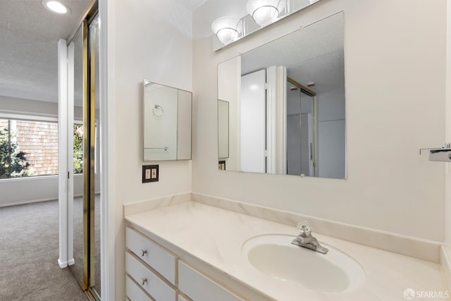 bathroom featuring baseboards, a textured ceiling, and vanity