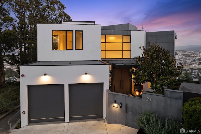 modern home with a garage, driveway, fence, and stucco siding