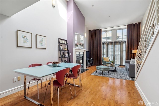 dining space featuring light wood-type flooring and a high ceiling