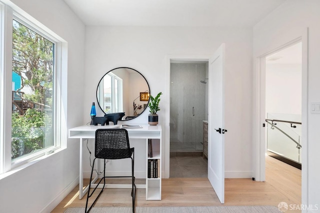 office with light hardwood / wood-style flooring and a healthy amount of sunlight