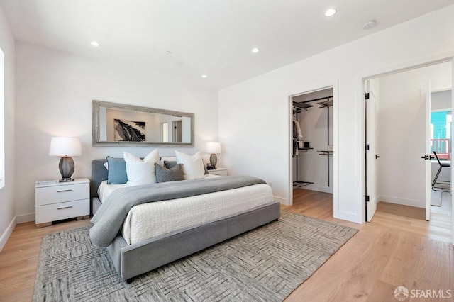 bedroom with a spacious closet, a closet, and light hardwood / wood-style floors