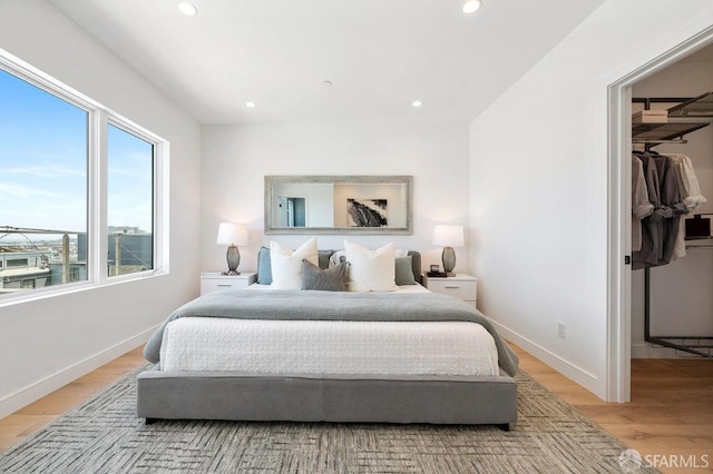 bedroom with light wood-type flooring and a spacious closet