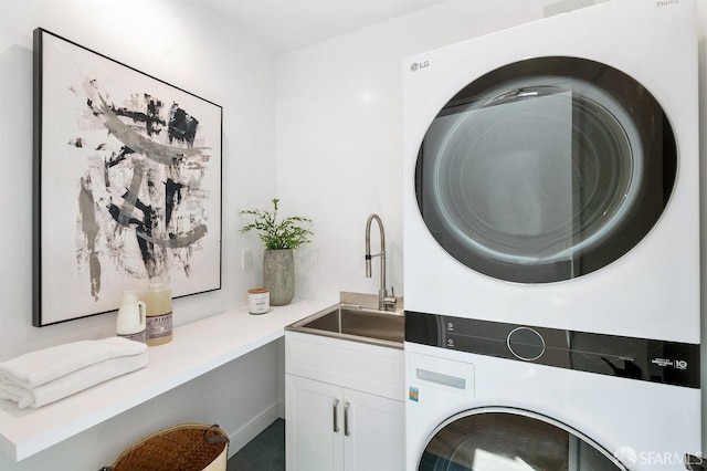 laundry room with cabinets, sink, and stacked washing maching and dryer