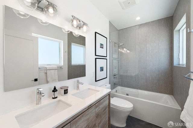 full bathroom featuring tiled shower / bath combo, vanity, and toilet