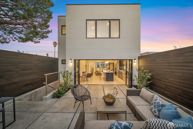 back house at dusk featuring an outdoor living space and a patio area