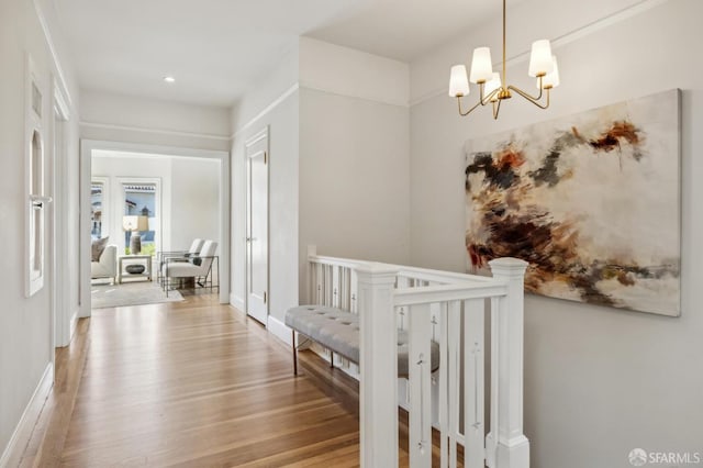 hallway with a notable chandelier and light wood-type flooring