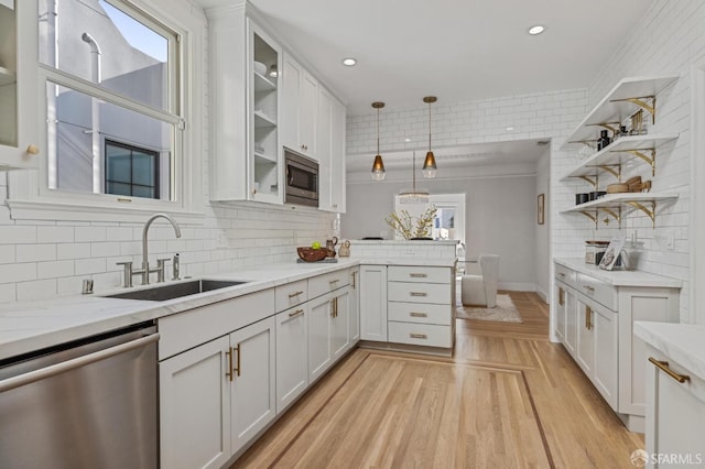 kitchen with stainless steel appliances, white cabinetry, hanging light fixtures, and sink