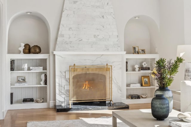 interior space featuring built in shelves, a premium fireplace, and hardwood / wood-style flooring