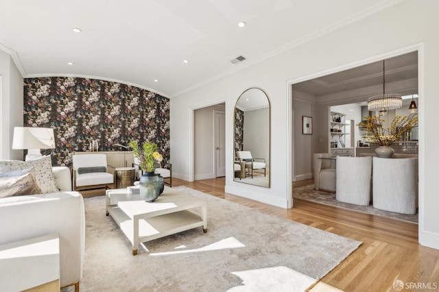 living room featuring ornamental molding, a chandelier, and wood-type flooring