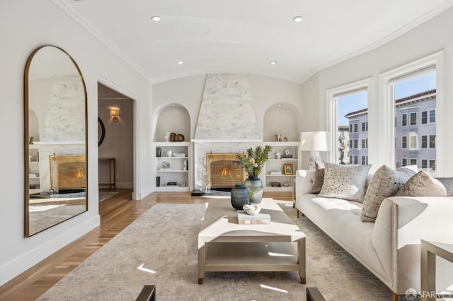 living room featuring lofted ceiling, built in shelves, a high end fireplace, and ornamental molding