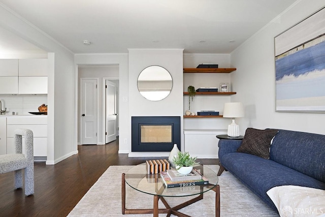 living room with baseboards, wood finished floors, a fireplace, and ornamental molding