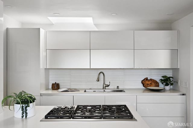 kitchen with a sink, light countertops, modern cabinets, and stainless steel gas cooktop