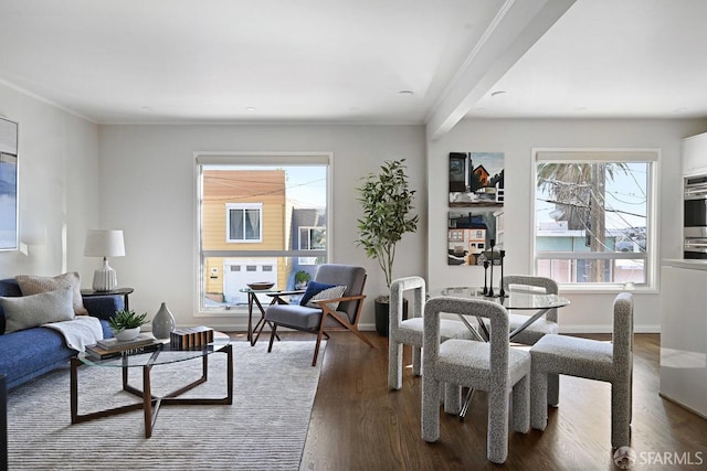 living area with dark wood-type flooring, baseboards, and ornamental molding