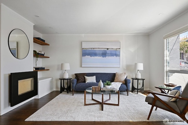 living area with a fireplace, crown molding, wood finished floors, and baseboards