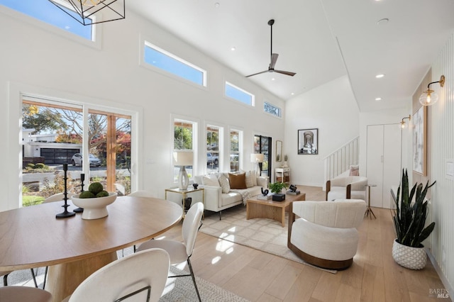 living room featuring light hardwood / wood-style floors, a high ceiling, and ceiling fan