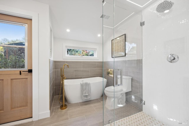 bathroom with independent shower and bath, toilet, tile patterned floors, and tile walls