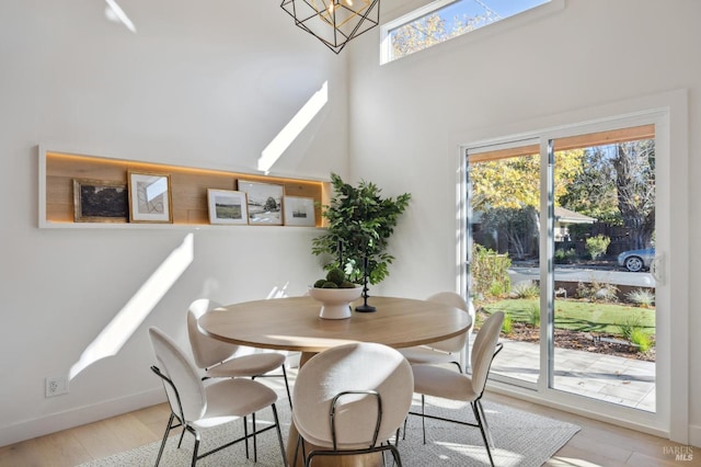 dining area featuring a towering ceiling, a chandelier, and light hardwood / wood-style flooring