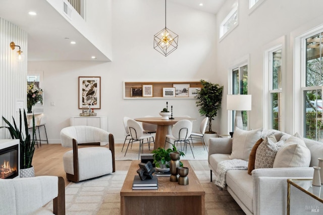 living room with light hardwood / wood-style floors and a towering ceiling