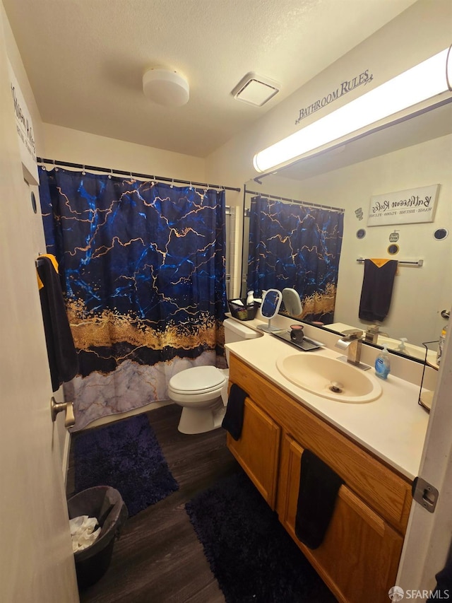 bathroom with vanity, a textured ceiling, hardwood / wood-style flooring, walk in shower, and toilet