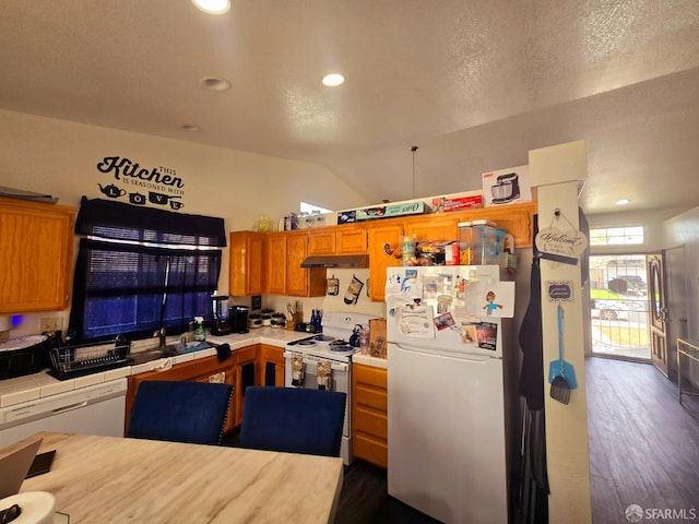 kitchen with sink, white appliances, tile countertops, dark hardwood / wood-style floors, and vaulted ceiling