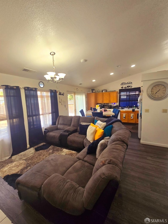 living room with an inviting chandelier, a textured ceiling, vaulted ceiling, and dark hardwood / wood-style flooring