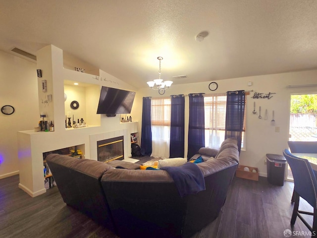 living room with a textured ceiling, a chandelier, a fireplace, vaulted ceiling, and dark hardwood / wood-style flooring