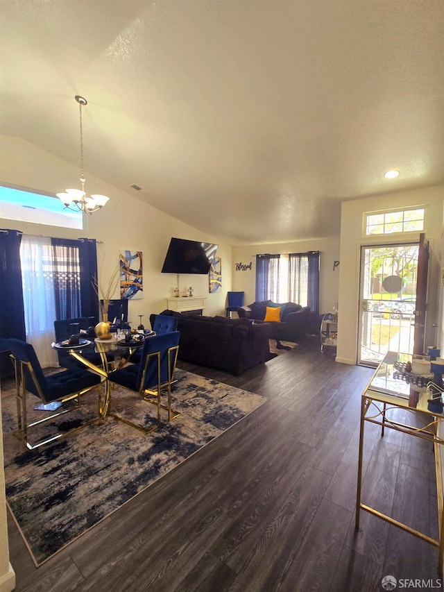 living room featuring an inviting chandelier, dark hardwood / wood-style floors, and vaulted ceiling