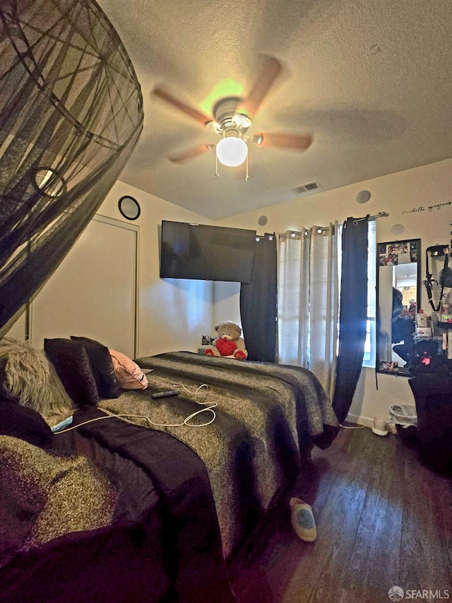 bedroom featuring wood-type flooring, vaulted ceiling, ceiling fan, and a textured ceiling