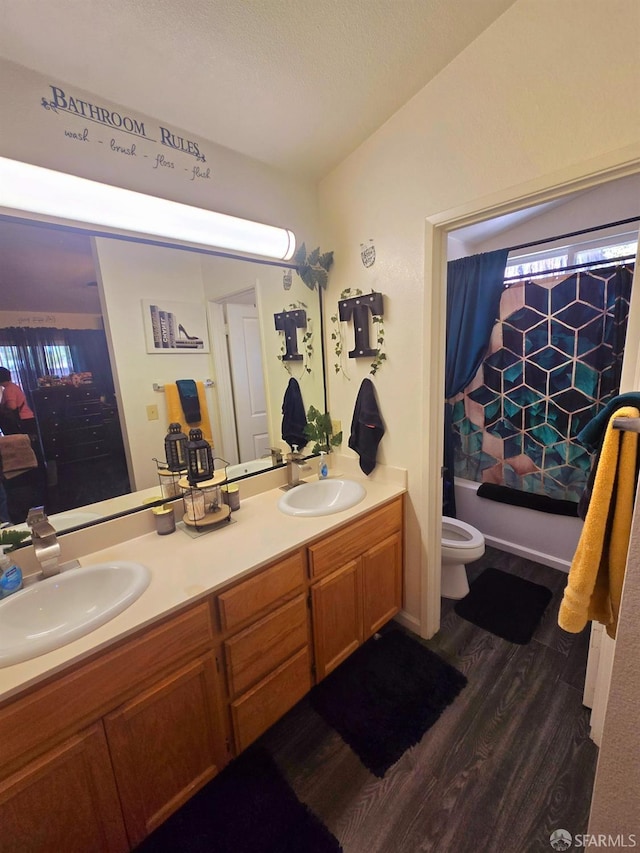 full bathroom featuring wood-type flooring, vanity, shower / tub combo, and toilet