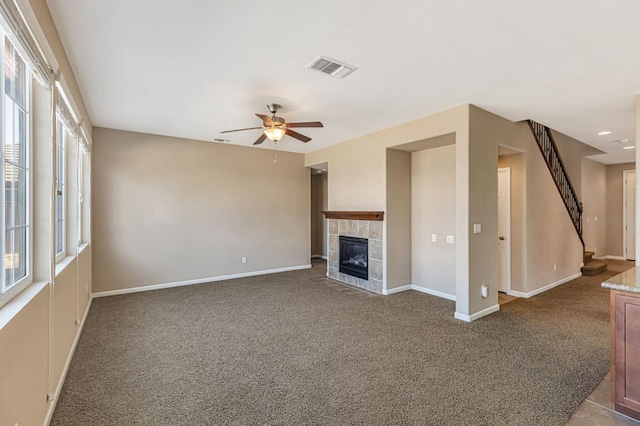 9877 Bluefin Way, Elk Grove, CA 95757 - unfurnished living room featuring carpet flooring, ceiling fan, a tile fireplace, and stairs