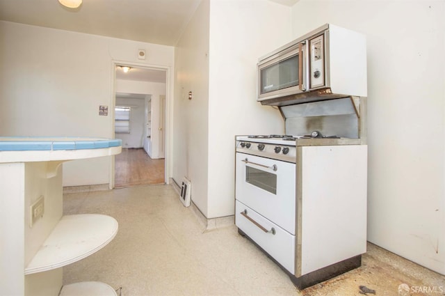 7520 Sunkist Dr, Oakland, CA 94605 - kitchen featuring tile counters, stainless steel microwave, light flooring, and white cabinets