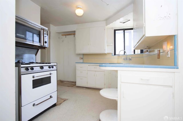 7520 Sunkist Dr, Oakland, CA 94605 - kitchen with stainless steel microwave, white gas range, and white cabinetry