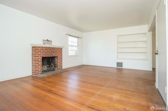 7520 Sunkist Dr, Oakland, CA 94605 - unfurnished living room featuring built in features, a fireplace, and wood finished floors