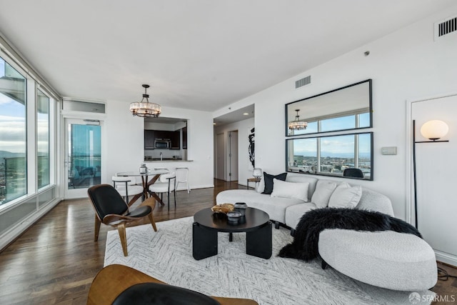 living area featuring visible vents, a chandelier, and dark wood finished floors