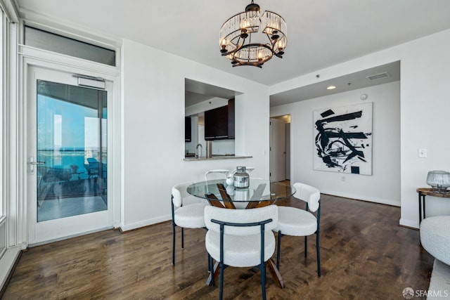 dining space with a notable chandelier, visible vents, baseboards, and wood finished floors