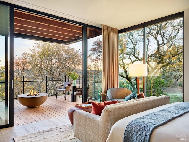 bedroom with light hardwood / wood-style flooring, expansive windows, and access to outside