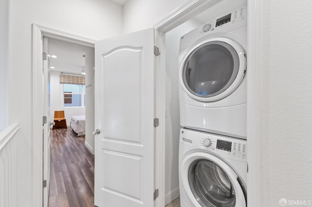 laundry area featuring stacked washer / drying machine and dark hardwood / wood-style floors