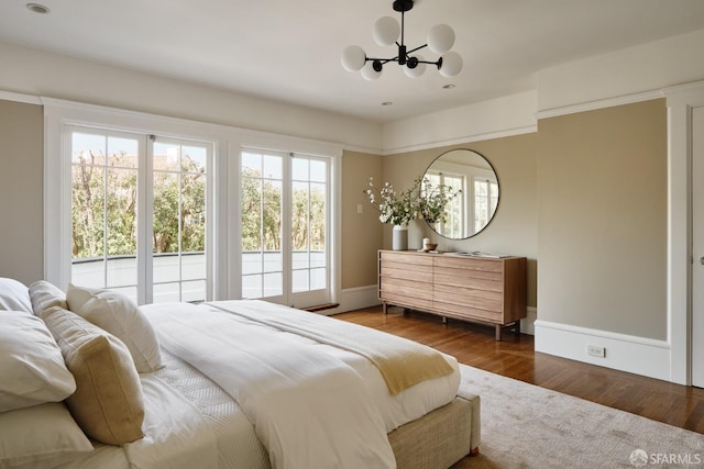 bedroom featuring an inviting chandelier, dark wood-style floors, and baseboards