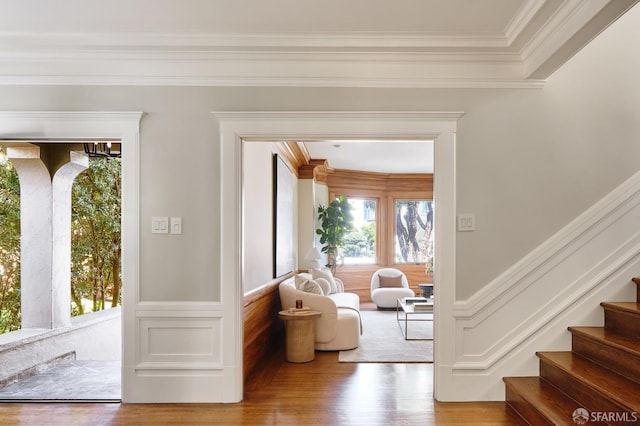 doorway to outside featuring wood finished floors, a wainscoted wall, stairs, and ornamental molding