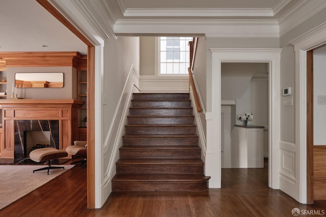 staircase featuring ornamental molding, a wainscoted wall, wood finished floors, and a decorative wall