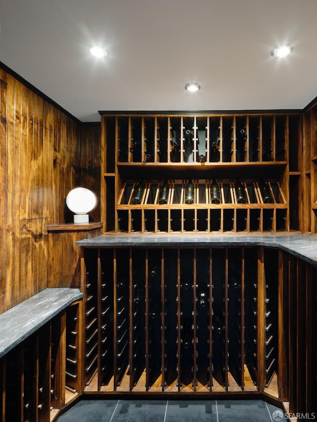 wine area featuring recessed lighting, tile patterned flooring, and wood walls
