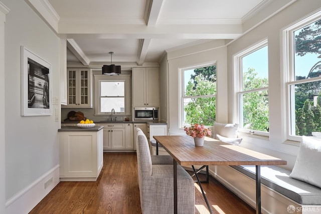 kitchen with stainless steel microwave, beamed ceiling, a sink, dark countertops, and dark wood finished floors
