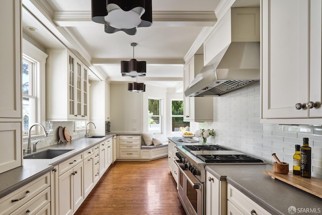 kitchen with crown molding, wall chimney exhaust hood, a sink, and range with two ovens