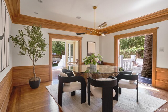 dining space featuring light wood-type flooring and a wainscoted wall