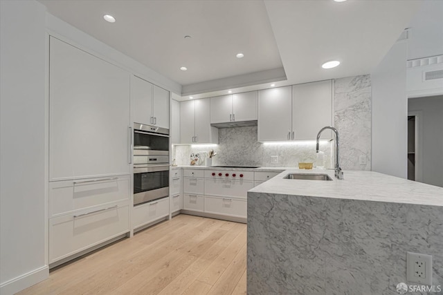 kitchen featuring white cabinetry, stainless steel double oven, kitchen peninsula, and sink