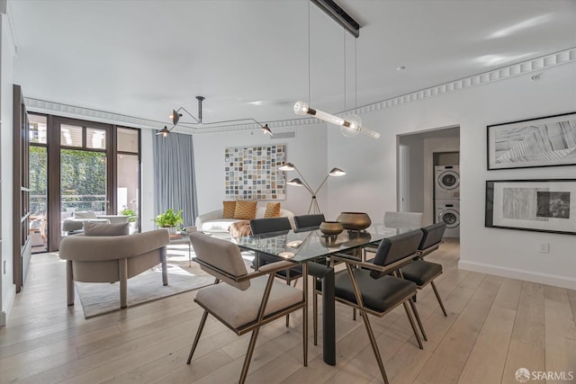 dining room with stacked washer / drying machine and light hardwood / wood-style flooring