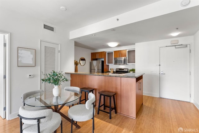 interior space with light hardwood / wood-style floors, stainless steel appliances, a breakfast bar, and kitchen peninsula