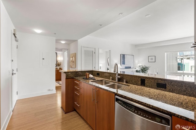 kitchen with sink, light hardwood / wood-style flooring, dark stone counters, and dishwasher